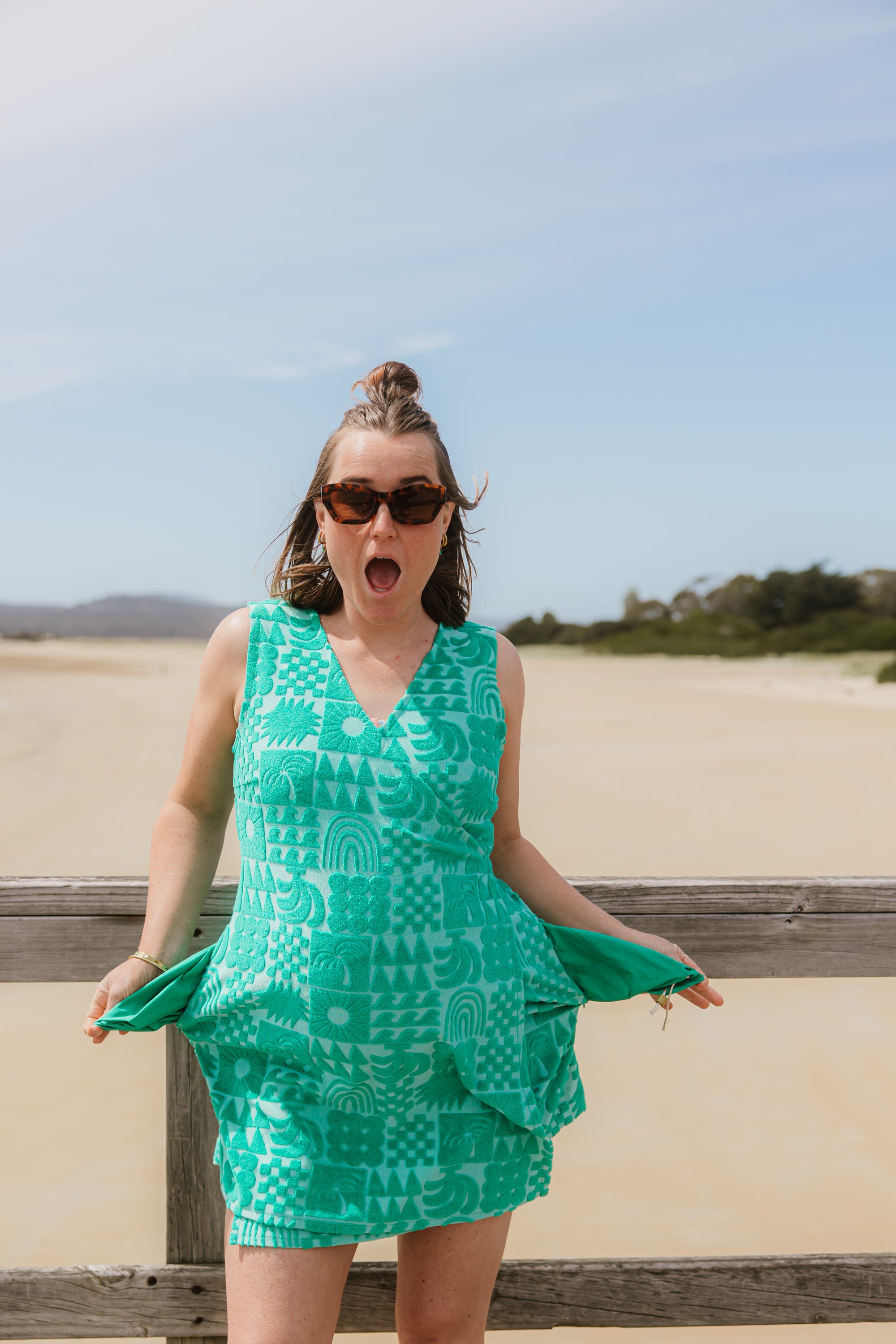 Woman wearing Sprout green terry wrap dress at the beach. Close up view of water-resistant side pockets.