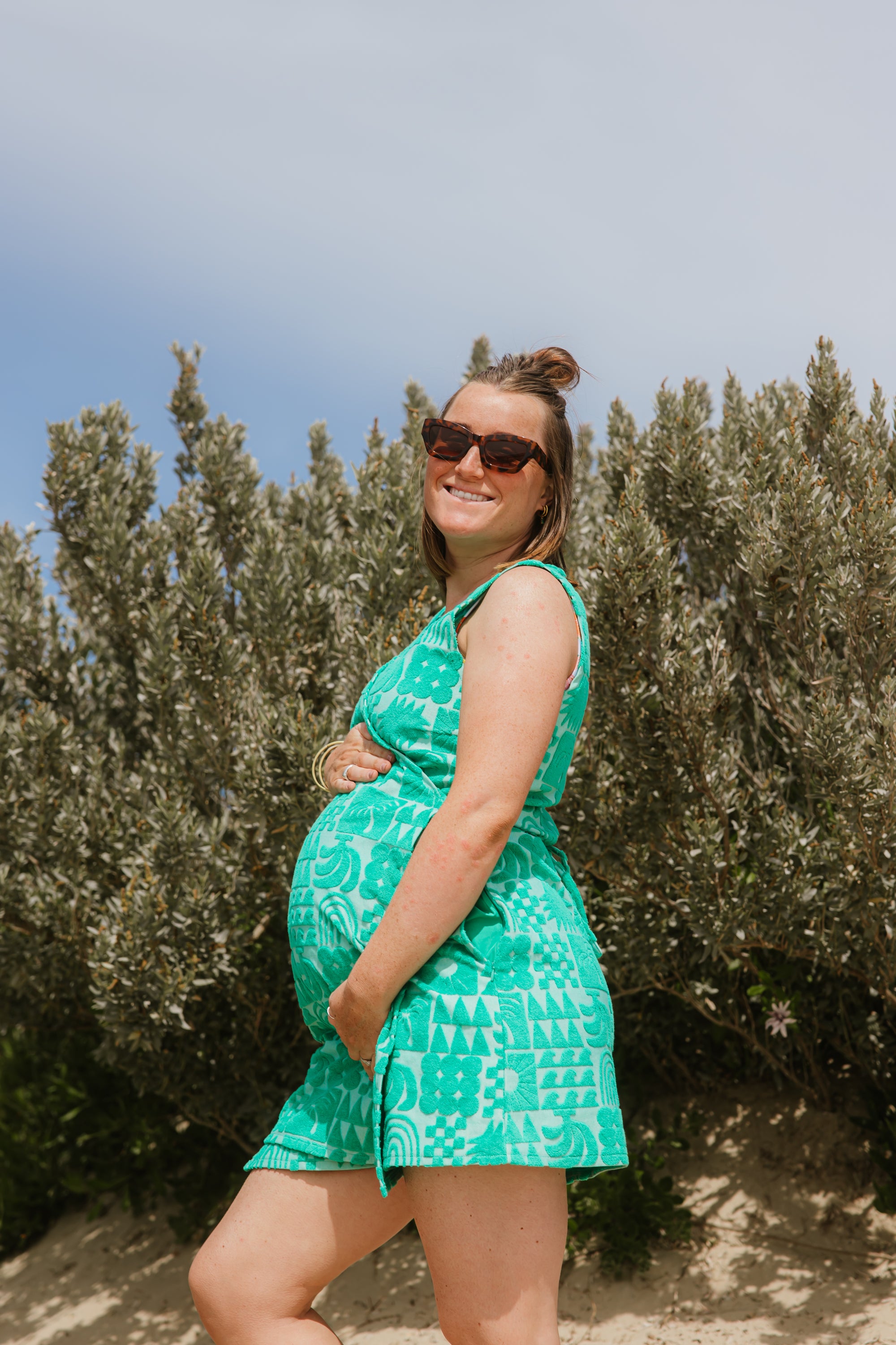 Pregnant woman wearing Sprout green terry wrap dress at the beach
